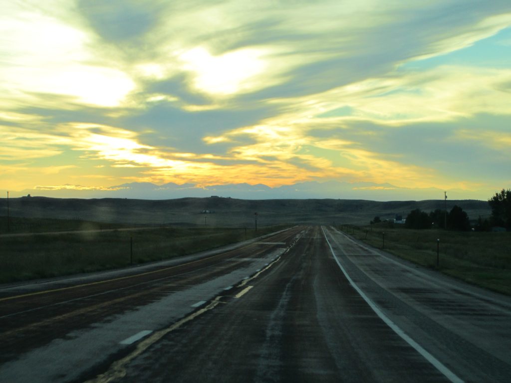 Empty road stretching into wide horizons and a distant sunset, representing the many possibilities of financial freedom.