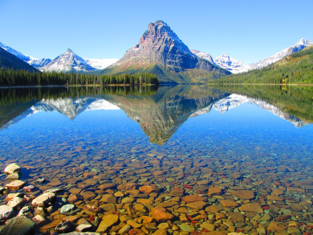 A mountain in the distance mirrored in a lake that is clear as glass. The photo illustrates the beauty, serenity, and peacefulness of the financially free lifestyle.