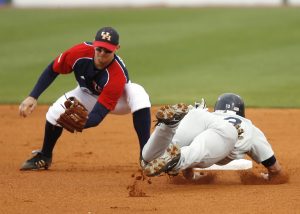 A baseball infielder making a play at the bag on a diving base-runner, illustrating the need to cover your budgeting bases in order to win with money.