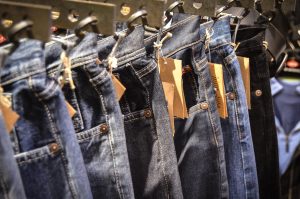 Jeans with price tags hanging on a retail clothes rack, illustrating the need to make a list of your savings goals and check the price tags on each.