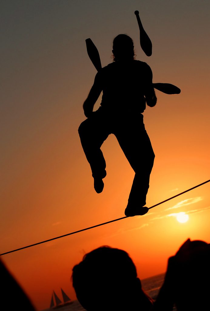 A tightrope walker juggling pins, illustrating a mastery of the budgeting balancing act.