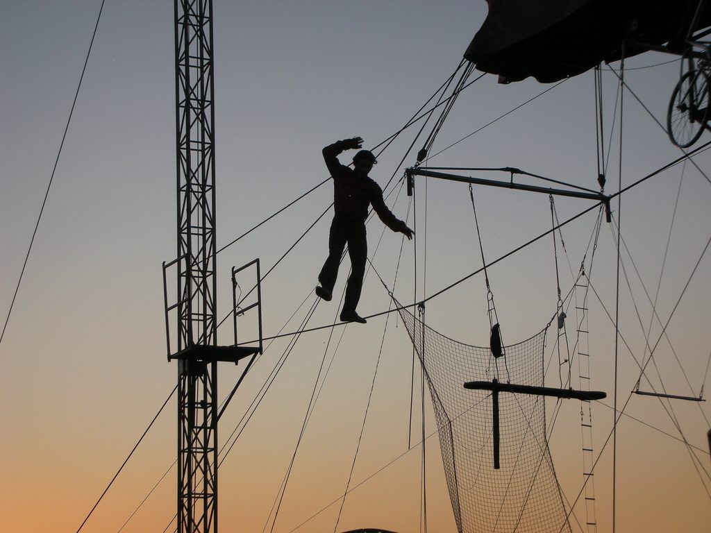 A tightrope walker high in the air, illustrating the high stakes of striking the right balance between savings goals and discretionary spending in your budget.