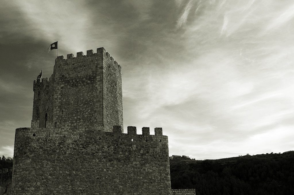 The battlements of a foreboding castle silhouetted against the sky, comparing the onerous bank fees charged by some institutions to the nefarious behavior of medieval robber barons.