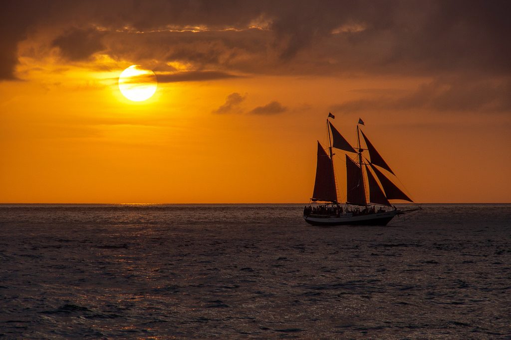 A sailboat cruising at sunset, illustrating the freeing power of automatic bill pay.