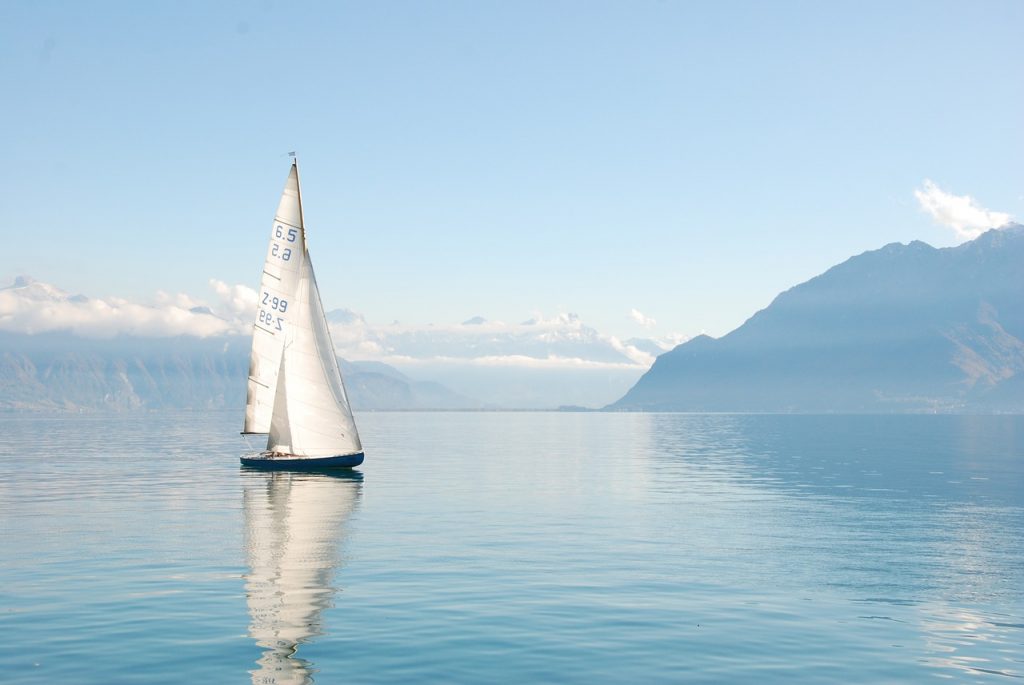 A sailboat on a serene mountain lake, illustrating how automatic bill pay offers you the chance for leisure and a simplified life.