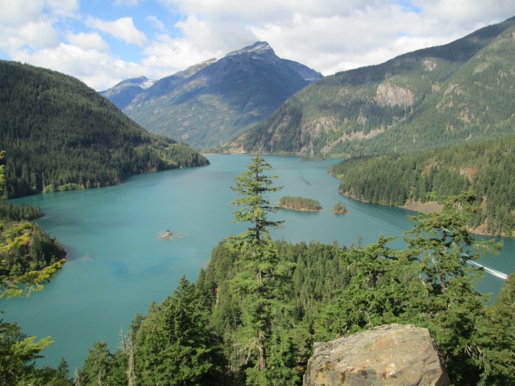 A mountain lake surrounded by the Cascades, filled with emerald-blue water as a result of light refraction on glacial silt suspended in it.